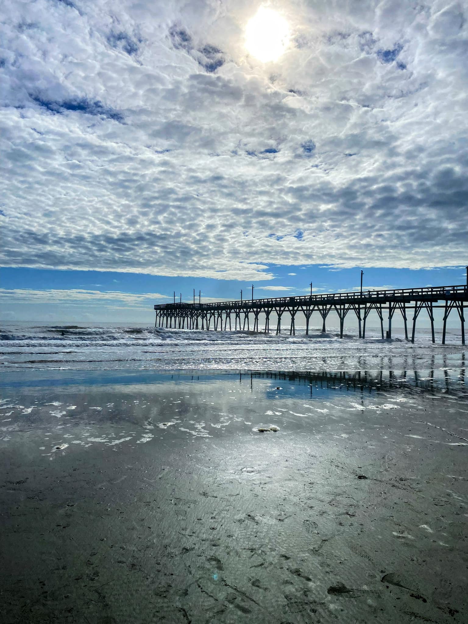 Sunset Beach pier reflected in wet sand